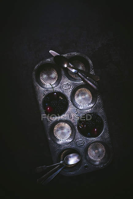 Poêle à cupcake vintage en métal avec des baies fraîches sur fond noir — Photo de stock