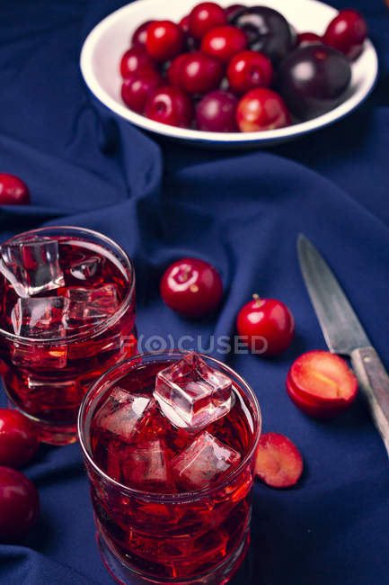 Rotes Getränk in der Nähe frischer Früchte auf blauem Tuch — Stockfoto