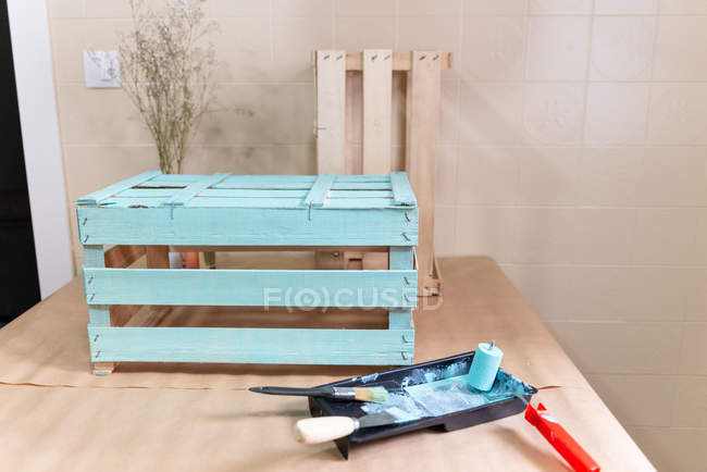 Свежеокрашенная деревянная коробка и инструменты на столе — стоковое фото