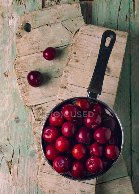 De dessus casserole pleine de prunes fraîches sucrées placées sur des planches de bois minables — Photo de stock