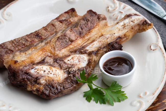 Tasty grilled meat dish served on white plate with barbecue sauce — Stock Photo