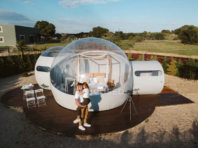 Aerial view of young couple kissing by unusual bubble hotel — Stock Photo