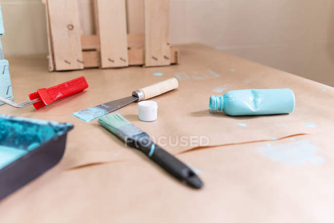 Boîte en bois avec bouteille de peinture et outils sur la table — Photo de stock