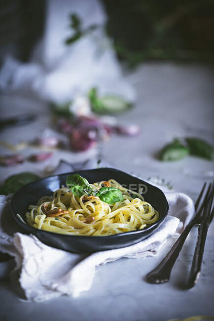 From above appetizing pasta with vegetables basil in black bowl on served table — Stock Photo