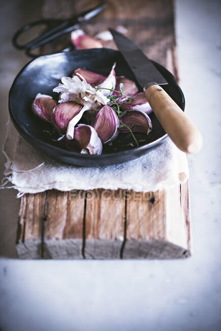 Dall'alto aglio maturo pronto per esser pulito con coltello in boccia nera su cavalletto di legno — Foto stock