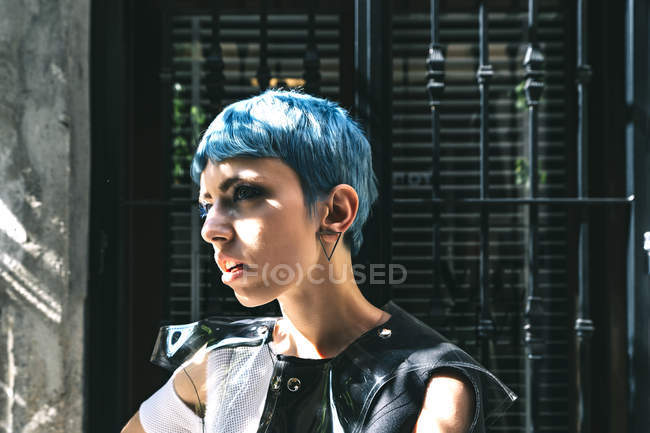Young woman in futuristic dress standing on street against old window building in sunlight — Stock Photo