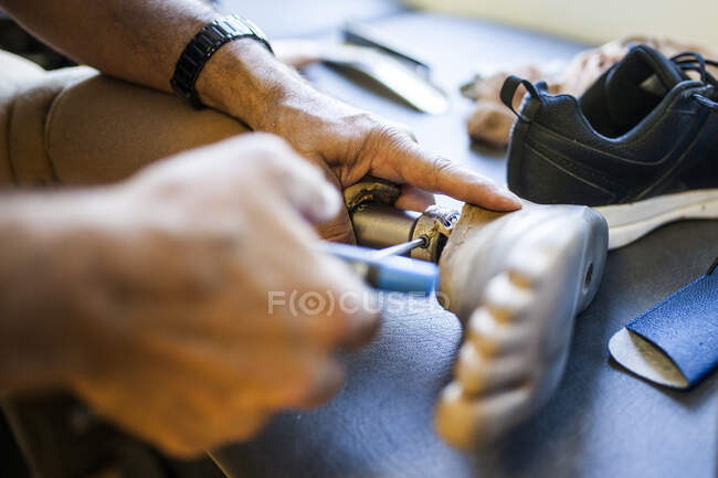Unrecognizable prosthetic engineer reviewing the prosthesis of a patient and improving the material in his workshop — Stock Photo