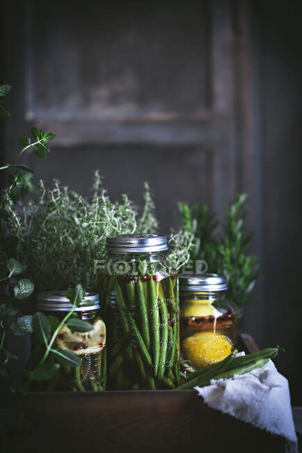 Состав горшечного растения, лимонов и стеклянной банки с сырыми зелеными бобами в деревянной коробке — стоковое фото