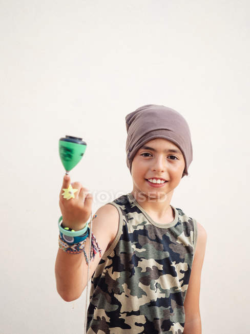 Смарт-стильний хлопчик в капелюсі легко обертається зеленим верхом, дивлячись на камеру на білому тлі — стокове фото