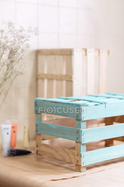 Частково пофарбована синя дерев'яна коробка на покритому паперовим столом — стокове фото