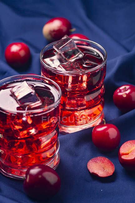 Bebida roja cerca de frutas frescas en tela azul - foto de stock