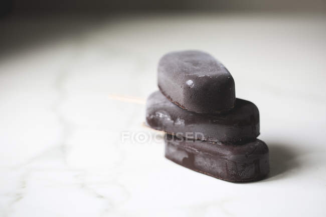 Ghiaccioli di gelato al cioccolato impilati sulla superficie di marmo — Foto stock