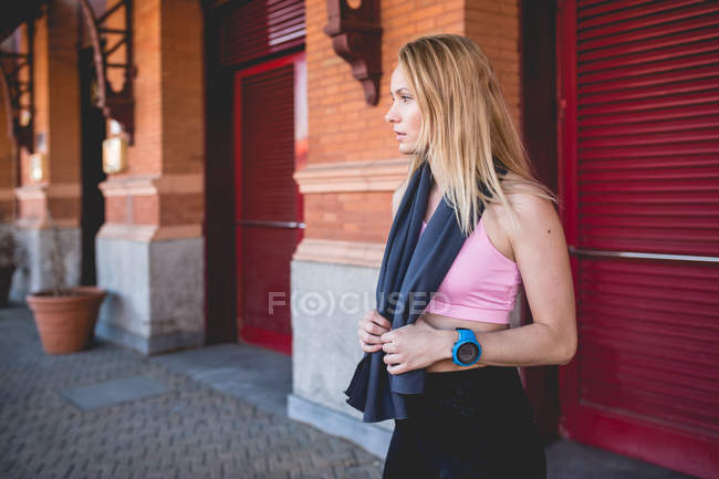 Jeune femme caucasienne blonde se reposer d'une session de course avec serviette enveloppée dans le cou — Photo de stock