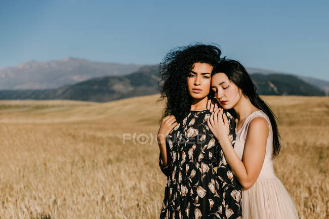 Жінка з закритими очима, спираючись на плече друга, стоячи в полі з сухою травою біля пагорбів — стокове фото