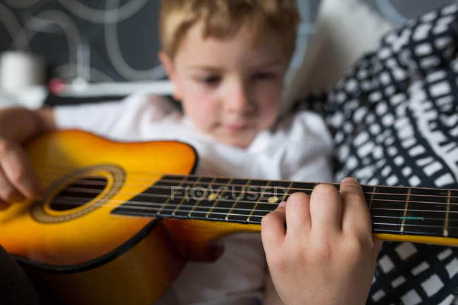 Joven chico rubio tocando guitarra de juguete - foto de stock