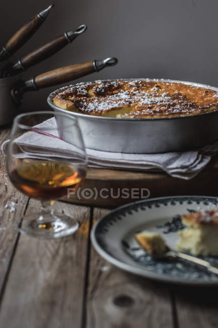 Pouding au fromage cottage servi dans une assiette sur serviette et verre de cognac sur table en bois — Photo de stock