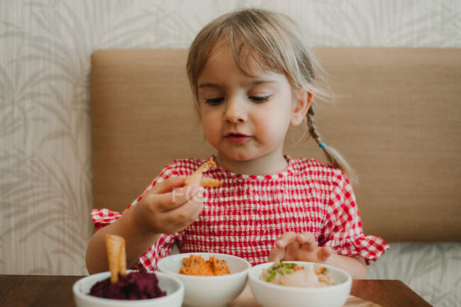 Carino bambina mangiare assaggio assortiti spuntino appetitoso a tavola — Foto stock