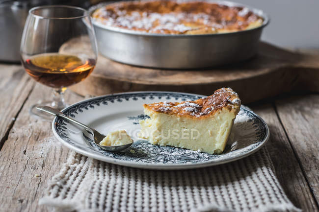 Hüttenkäse gebackenen Pudding auf Teller auf Handtuch und Glas Cognac auf Holztisch serviert — Stockfoto