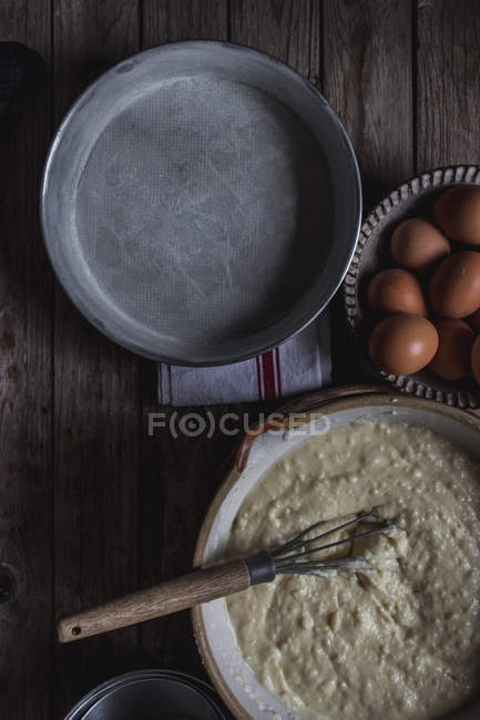 С верхней выпечки блюдо с тестом для приготовления пирога на разделочной доске с яйцами на деревянном столе — стоковое фото