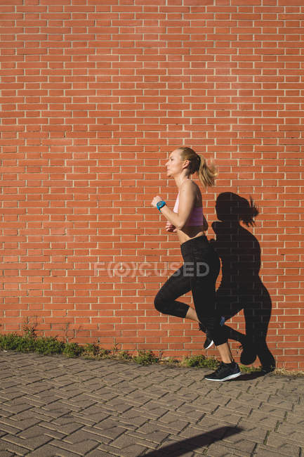 Beautiful blonde young caucasian woman jogging outdoors — Stock Photo