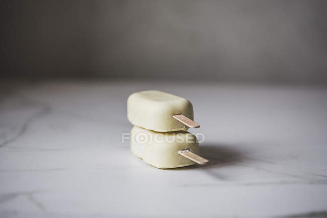 Eis am Stiel aus weißer Schokolade auf Marmoroberfläche gestapelt — Stockfoto