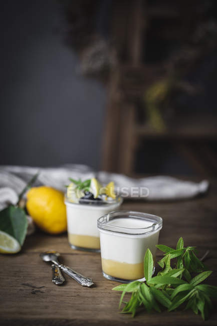 Bicchieri con yogurt fatto in casa e cagliata di limone sulla superficie di legno — Foto stock