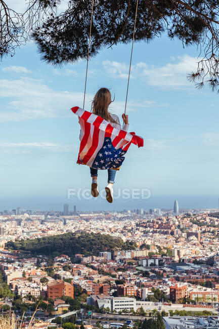 Junges Mädchen feiert den 4. Juli mit der amerikanischen Flagge auf einer Schaukel — Stockfoto