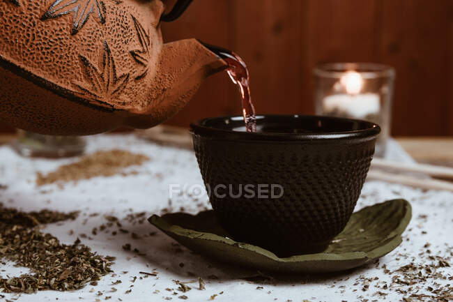 Подача ароматного смачного чаю в чашці глиняного чайника та солодких дат на білому підносі, прикрашеному чайним листям на дерев'яному фоні — стокове фото