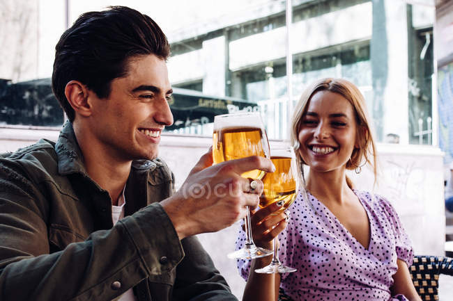 Cheerful young attractive couple enjoying refreshing drinks during walking in town — Stock Photo