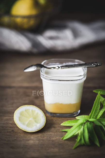 Verre de yaourt maison et de caillé de citron sur une surface en bois — Photo de stock