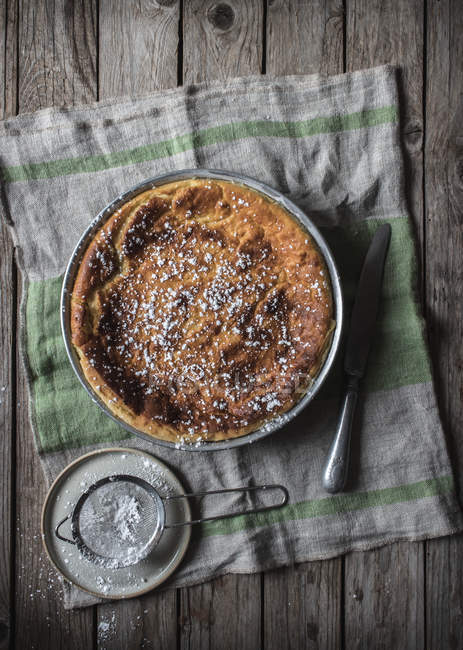 Cottage cheese baked pudding served on towel near powdered sugar on wooden table — Stock Photo