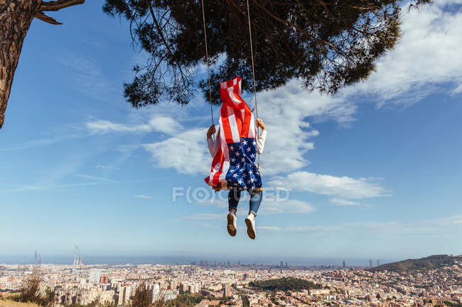 Young girl celebrating the 4th of July with the American flag on a swing — Stock Photo