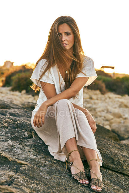 Jovem mulher sentada e posando na rocha — Fotografia de Stock