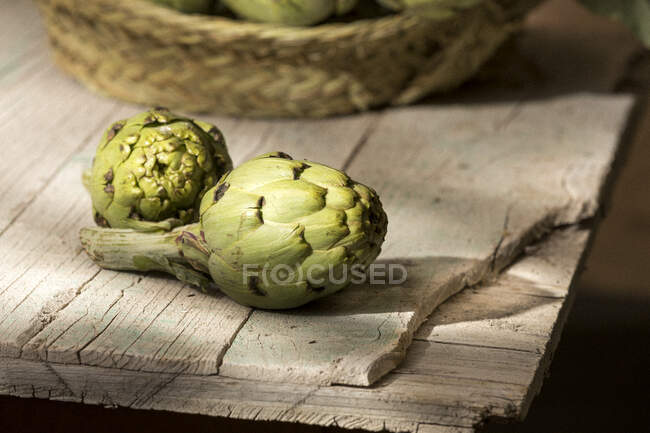 Alcachofa fresca en una antigua superficie de madera agrietada en interiores - foto de stock