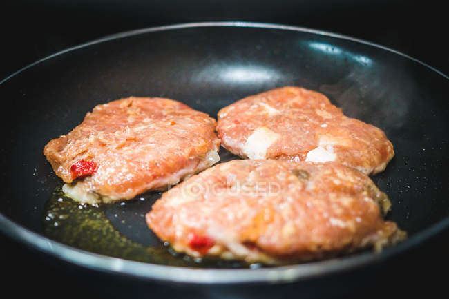 Closeup deliciosas costeletas de carne fritar em óleo na panela quente na cozinha — Fotografia de Stock
