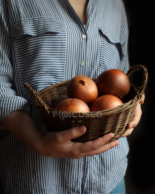 Oignons mûrs ronds dans un panier en osier brun — Photo de stock
