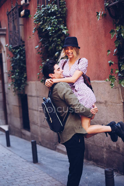 Веселый молодой человек веселится и носит подружку во время городского свидания — стоковое фото