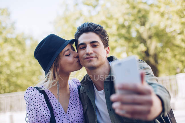 Junger schöner Mann macht Selfie mit Freundin beim Küssen im schönen Garten — Stockfoto