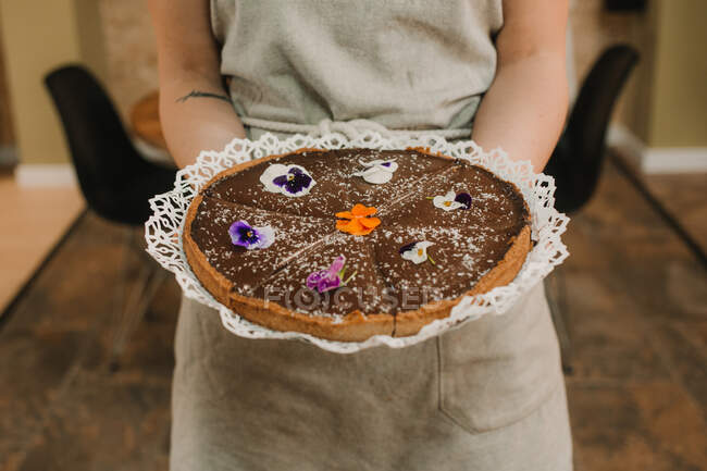 Par-dessus savoureux gâteau appétissant décoré avec des fleurs vives dans les mains de la femme — Photo de stock