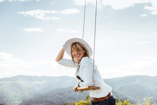 Menina feliz com chapéu ao lado de um balanço ao pôr do sol — Fotografia de Stock