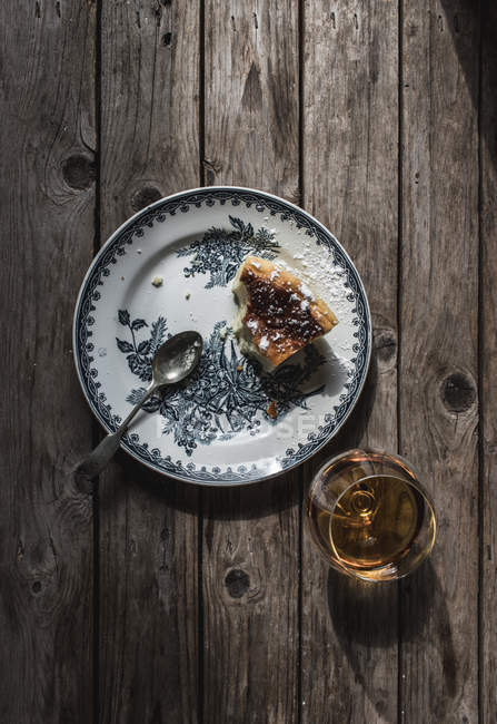 Draufsicht auf Scheibe Hüttenkäse gebackener Pudding auf Teller und Glas Cognac auf Holztisch — Stockfoto