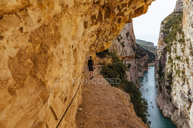 Vista posteriore dell'uomo irriconoscibile che cammina attraverso una gola vicino a un fiume — Foto stock