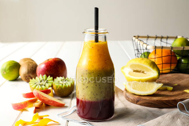 Glasflasche mit Schichten köstlicher Frucht-Smoothie mit Stroh auf weißem Tisch — Stockfoto