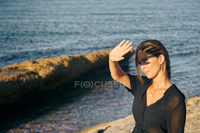 Young attractive woman covering face from sun on beach — Stock Photo
