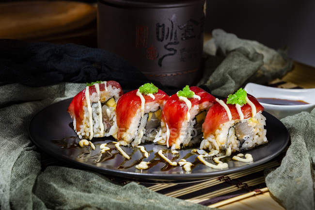 Delicioso sushi colorido con atún y hierbas verdes en la mesa servida en el restaurante - foto de stock
