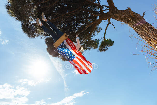 Дівчинка святкує 4 липня з американським прапором на гойдалці — стокове фото