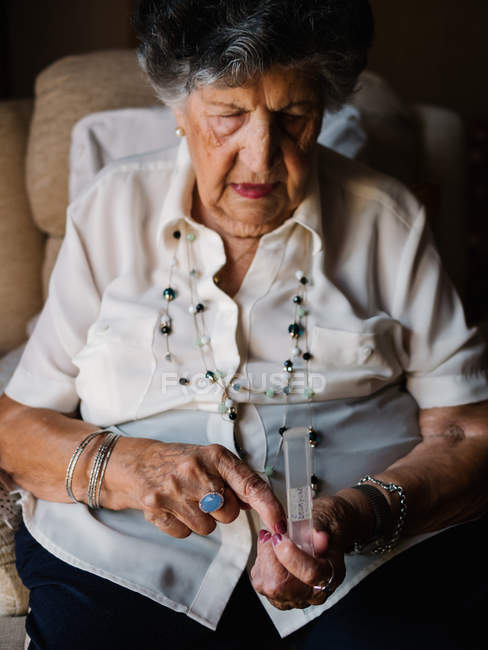 Mulher sênior elegante tomar pílulas, sentado em poltrona em casa — Fotografia de Stock