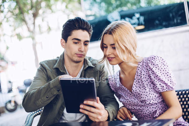 Allegro giovane coppia attraente utilizzando tablet digitale all'aperto in città — Foto stock