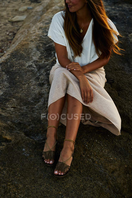 Молода жіноча модель сидить на скелі і дивиться вбік — стокове фото