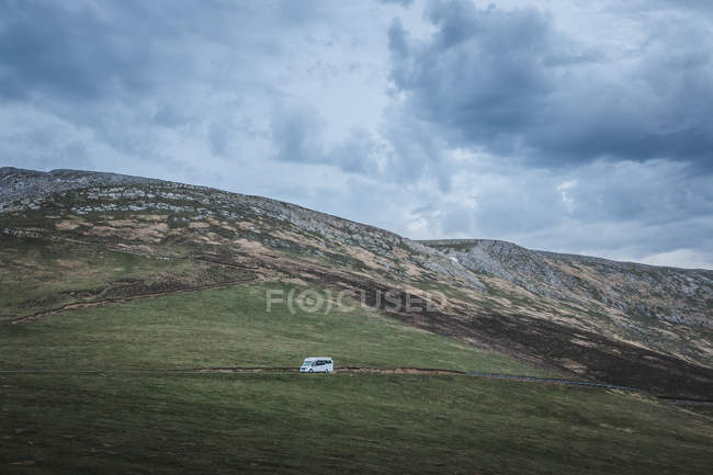 White camper riding along asphalt road on hillside during trip in alpine countryside — Stock Photo